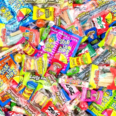 “Bright assorted sour candy mix featuring Warheads, Zotz, Sour Punch, Smarties, Laffy Taffy, and other colorful wrapped sweets, perfect for vending and candy crane machines.”