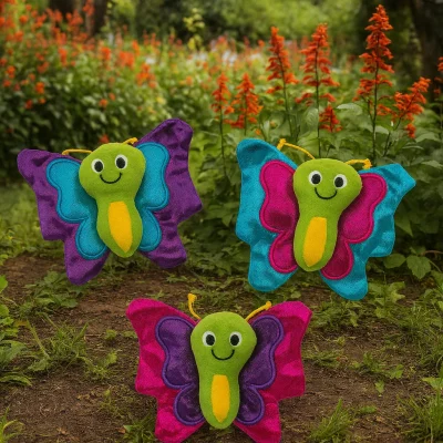 "Three colorful plush butterflies with smiling faces displayed in a garden setting with green plants and red flowers in the background."