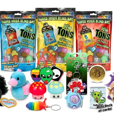 "Super Mega Blind Bag prize mix with three sealed blind bag packs behind assorted sample prizes including plush, keychains, squishies, and trinkets on a white background."