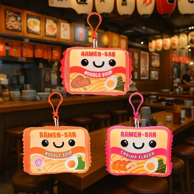 "Three plush ramen-themed backpack clip toys labeled Ramen-San, displayed inside a cozy ramen restaurant with warm lighting and wooden decor."