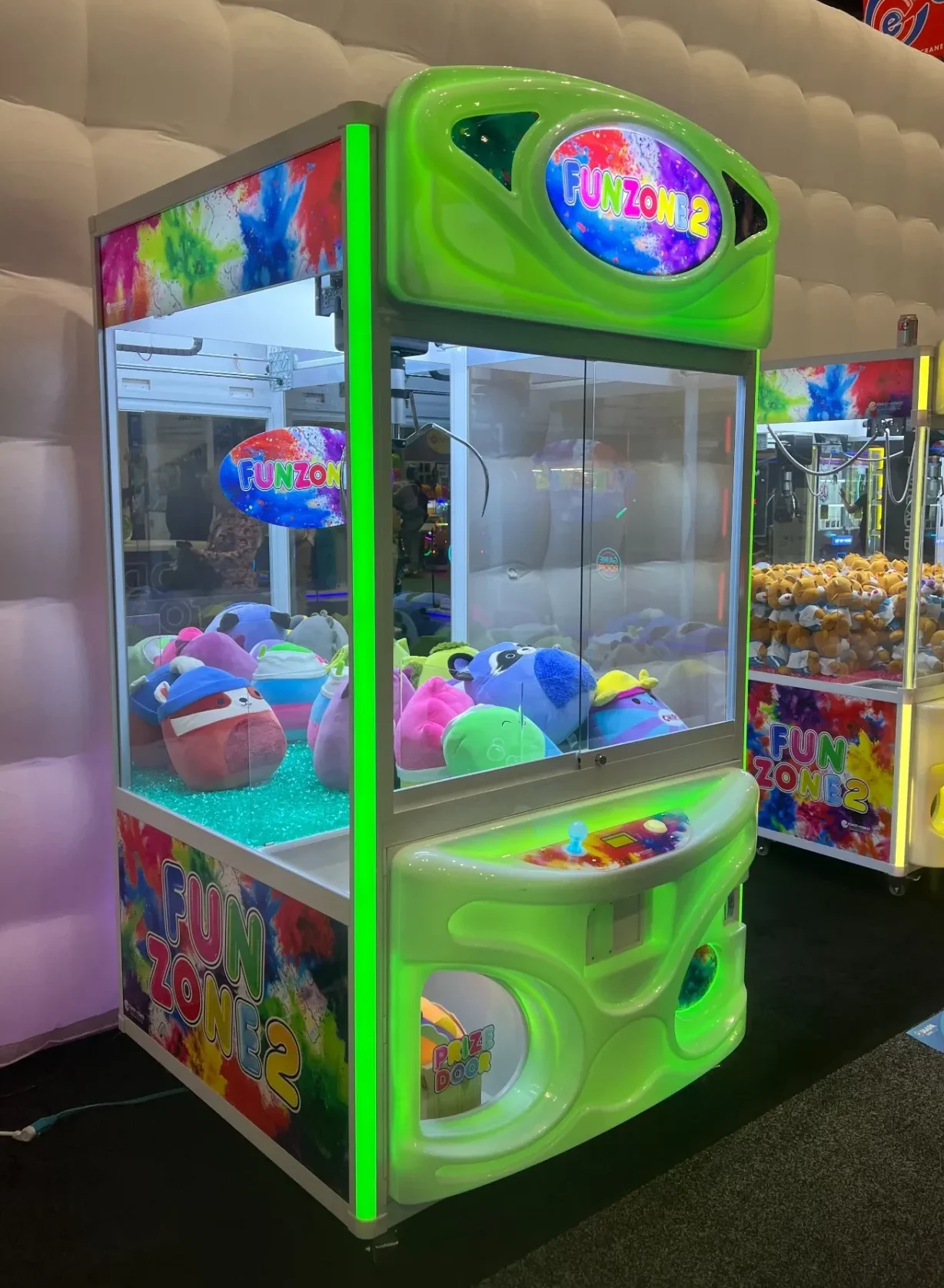 Fun Zone 2 crane machine with neon green cabinet and RGB lighting, loaded with medium plush at IAAPA 2025.