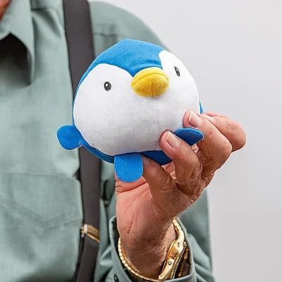 “Person holding a small round blue and white plush penguin toy, showing its size and soft texture for scale.”