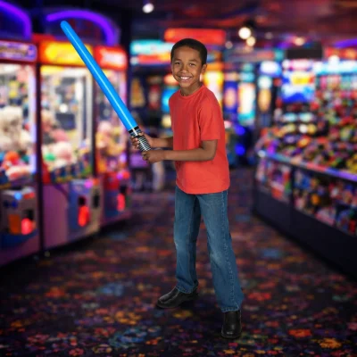 Child holding a blue inflatable light saber prize inside a family entertainment center arcade