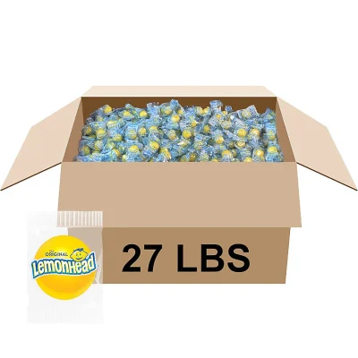 Open cardboard case filled with individually wrapped Lemonhead lemon hard candy, bulk 27 lb box with yellow lemon candy pieces