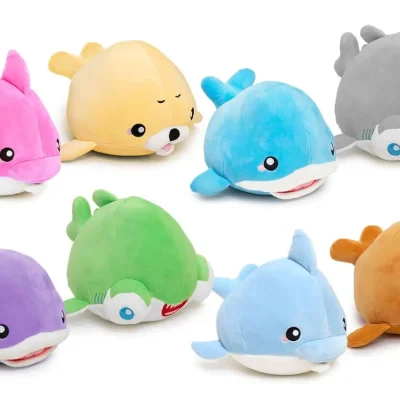 Assorted 7-inch sea animal plush mix featuring colorful dolphins, sharks, whales, and sea lion characters in pink, blue, green, purple, gray, yellow, and orange. Soft plush assortment for claw machines, redemption counters, arcades, and prize games.